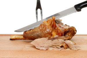 Carving roast leg of lamb joint on a wooden board