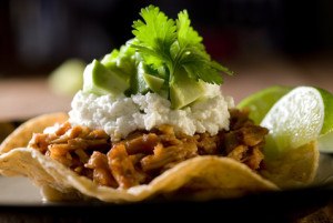 tostada topped with shredded pork, feta and vegetables.